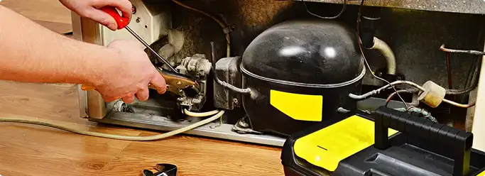 Refrigerator repair technician fixing the compressor and wiring in Mountain View, CA