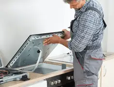 Appliance repair technician installing a built-in cooktop in San Jose, CA
