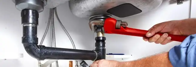 Garbage disposal repair technician tightening the sink drain and disposal connection in San Jose, CA