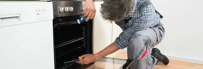 Oven repair technician inspecting and servicing an electric oven in San Jose, CA