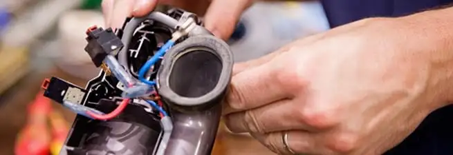 Vacuum repair technician reconnecting wiring and components in San Jose, CA